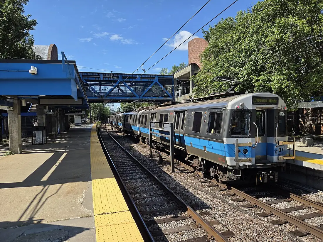 A blue and silver Blue Line train at the outdoor platform of Suffolk Downs station on a sunny day.